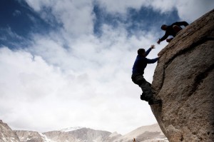 person helping aother on cliff